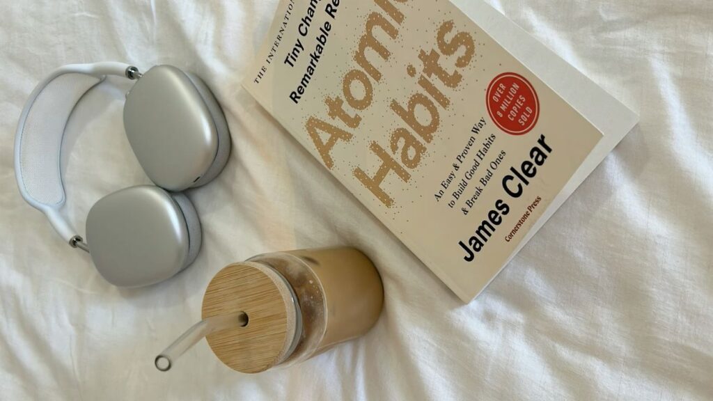 Coffee, book, and headphones on bed.